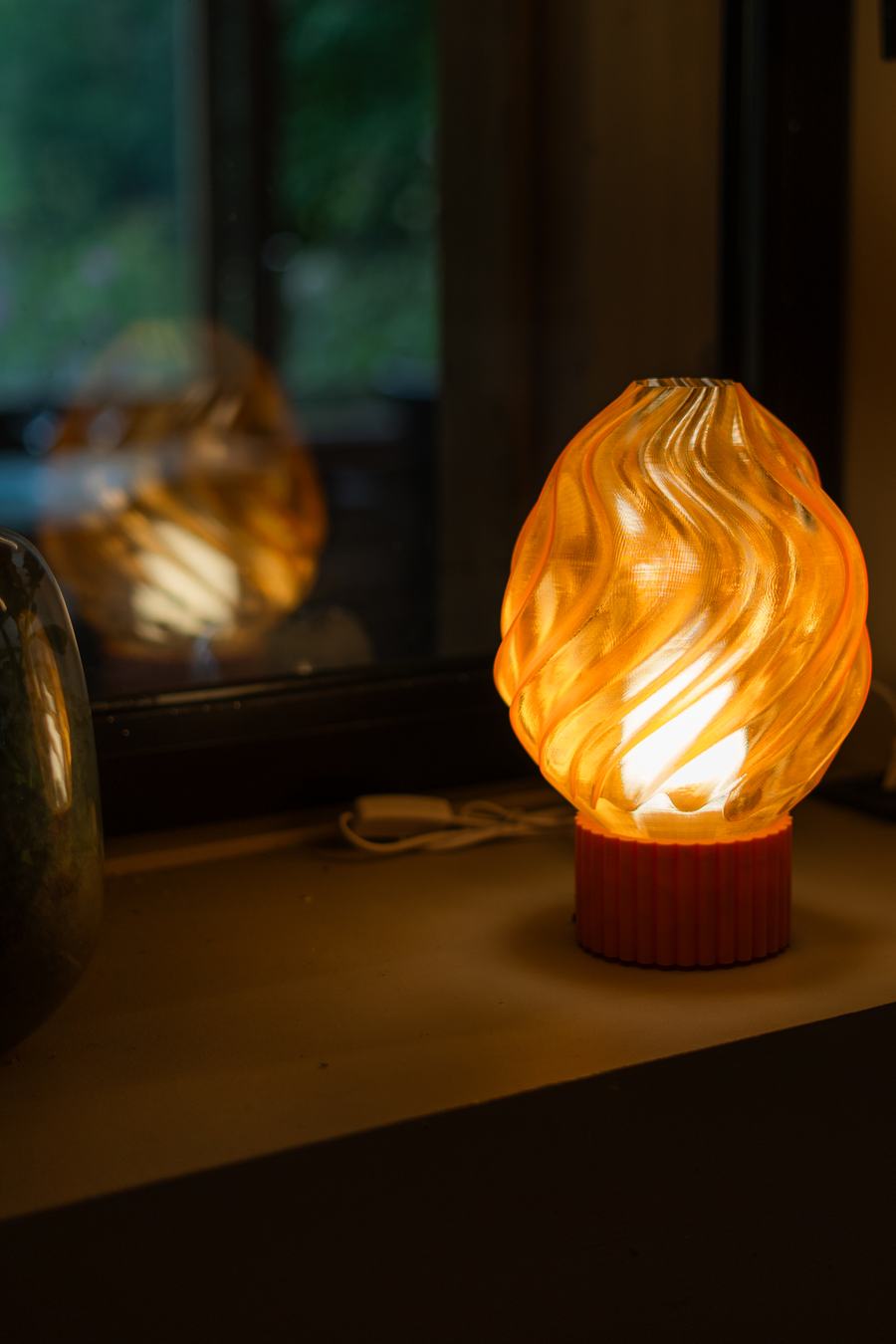 Lampe Métamorphe avec son diffuseur ambre Meringue allumé, posée près d'une fenêtre